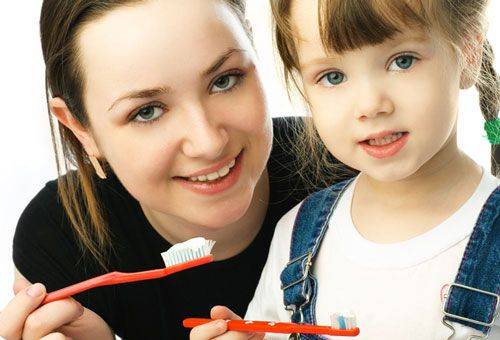 femme avec une fille avec des brosses à dents à la main