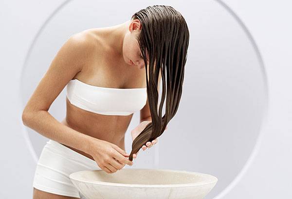 Une fille se lave la tête dans un bouillon d'herbes