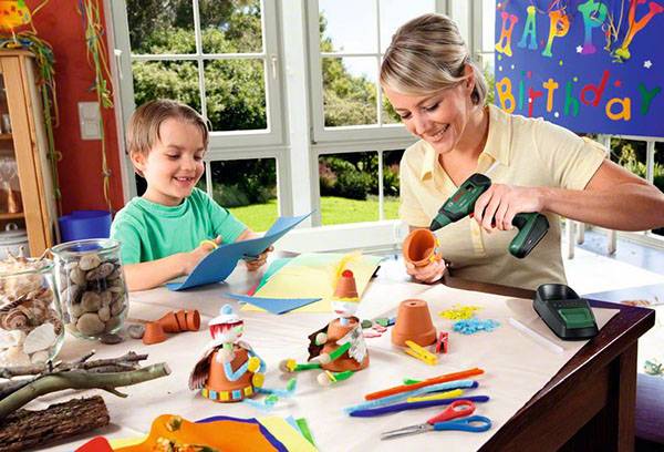 Maman avec un enfant colle artisanat avec un pistolet thermique