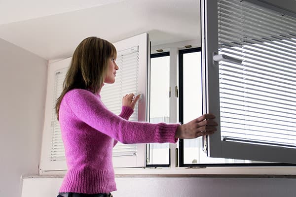 Fille ouvre une fenêtre pour aérer