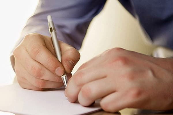 Un homme écrit dans un cahier