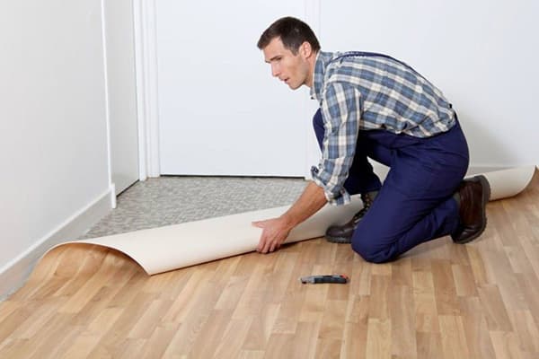 Un homme tisse un nouveau linoléum sur un vieux