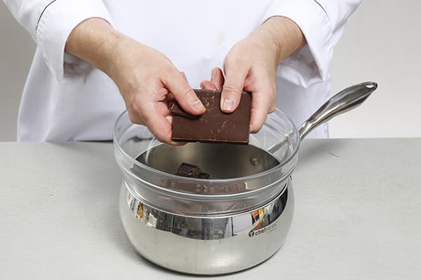 Un confiseur noie du chocolat dans un bain-marie